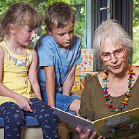 Oma beim vorlesen mit zwei Kindern.